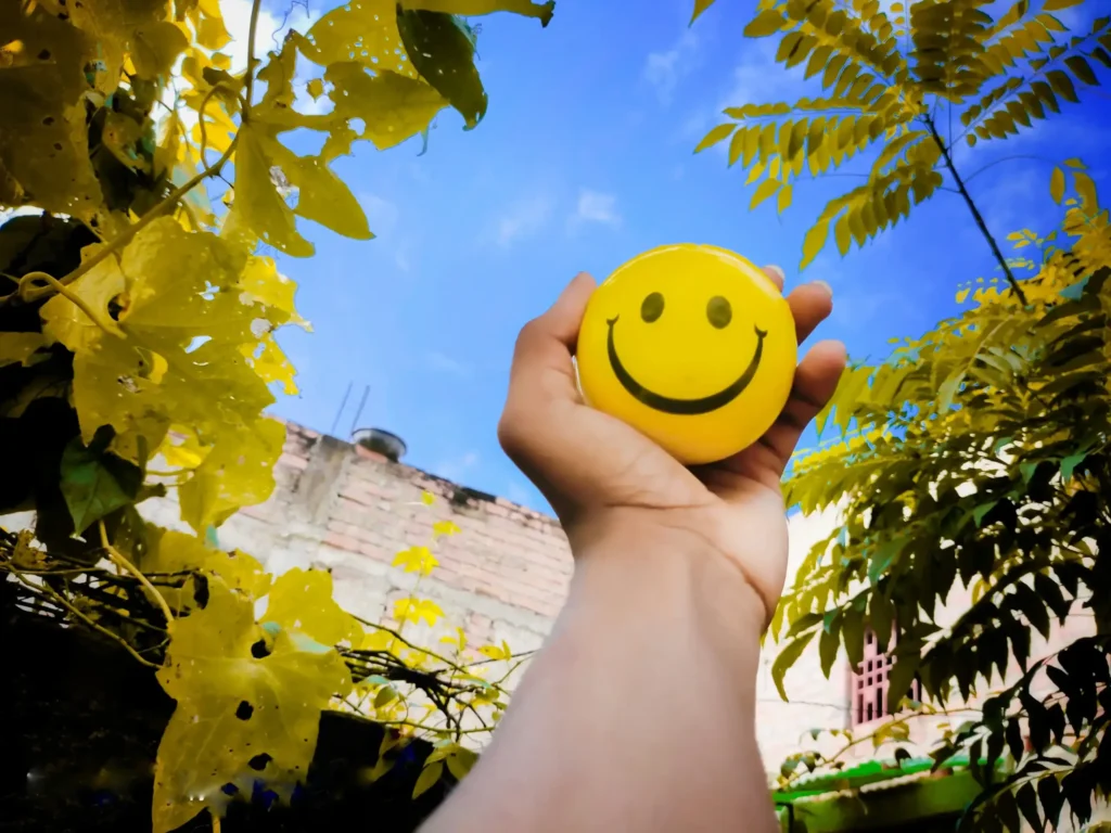 smiley ball in einer hand vor blauen himmel