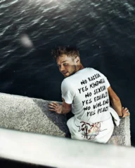 yes-men-ein-mann-mit-positiv-bedruckten-shirt-sitzt-am-hafen---